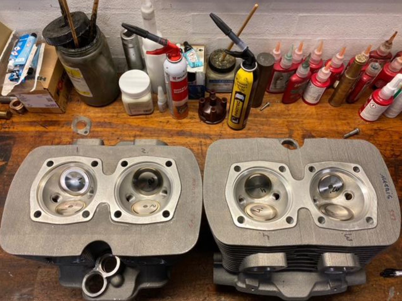 Two four-cam cylinder heads on a workshop bench