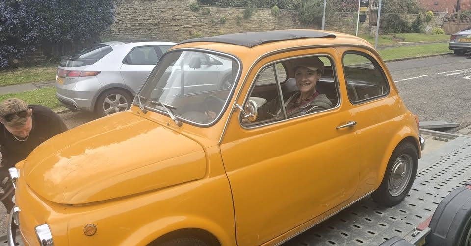 A yellow classic car on a flatbed for collection