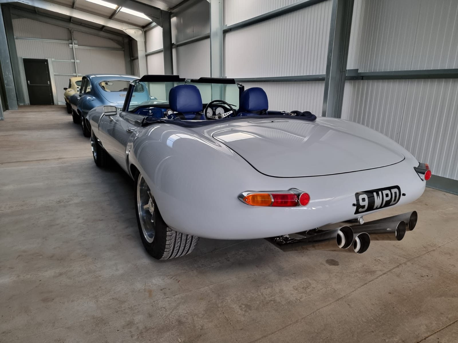 E-Type Re-Imagined — light grey convertible with the roof down in the workshop